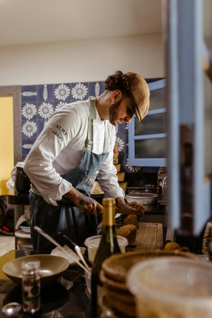 Chef in apron skillfully preparing a dish in a cozy, warmly lit kitchen ambiance.